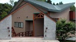 木々に囲まれた場所に立つ緑色の屋根のコテージの画像