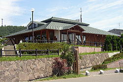 石垣の一段上に建てられている、瓦屋根で平家建ての小説「津軽」の像記念館の写真
