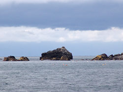 雲が広がる海で、奥に見えている小島や岩が続いている景色の写真