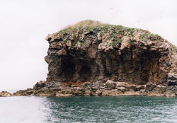 海の先に、神殿のような洞窟がある不思議な形の島の景色の写真