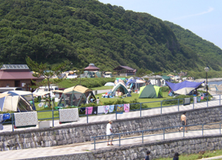 山のふもとにたくさんのテントが並ぶ折腰内オートキャンプ場の写真