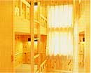 窓から光が差し込む壁が木の部屋に、木製の二段ベットがある画像