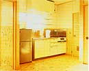 冷蔵庫と流し台が置いてある、壁が木造の開放的な台所の画像