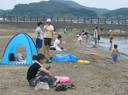 小型テントを立てて砂浜で遊ぶ家族の写真
