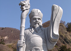 右手には竜の頭の杖を持ち、左手は着物の袖を持ち掲げている除福の像の写真