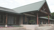入り口エントランスに緑色の三角屋根がある、ふれあいセンターの外観写真