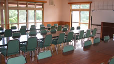 多目的ホールにたくさんの緑の椅子と横長の机が3列並んでいる写真