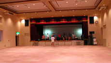 正面に舞台がある、明るい内装のイベントホールの写真