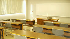 窓から明るい光が入る、長机と椅子が並んだ第1研修室の写真