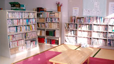 カーペットが敷かれた明るい畳の室内に、本棚が置かれてぎっしりと本が並べられている図書室の写真