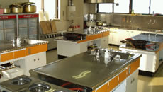 磨き上げられた調理台が並び、壁にはヤカンやまな板などがある調理体験実習室の写真