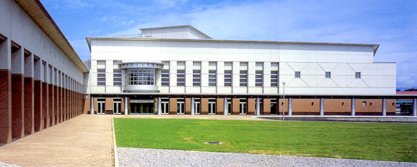 芝生の庭があるL字型のモダンなデザインの建物の、総合文化センター「パルナス」の外観写真