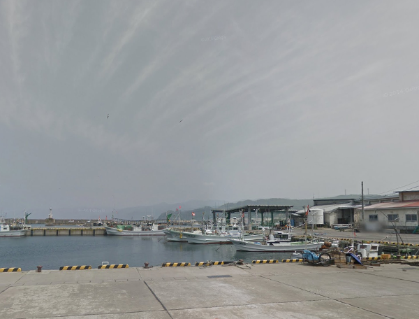 曇り空を背景に映した小泊漁港の写真