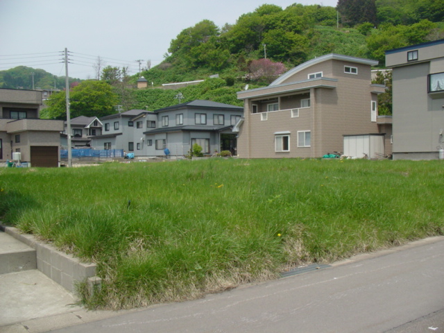 住宅街の一角の、草地になった分譲地の写真